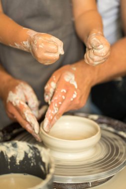 İnsan eli çömlekçi çarkında kilden bir ürün yapar.