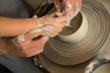 İnsan eli çömlekçi çarkında kilden bir ürün yapar.