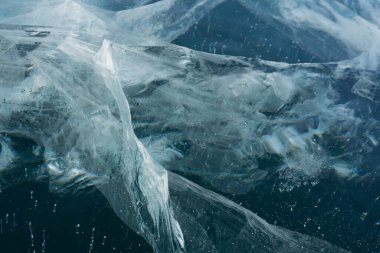 Kışın şeffaf mavi gölde ince buz çatlakları