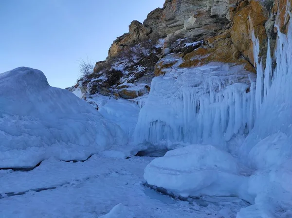 Rochers recouverts de neige et de glace près d'un lac recouvert de glace — Photo