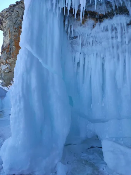 Rochas cobertas de neve e icicles perto de um lago coberto de gelo — Fotografia de Stock