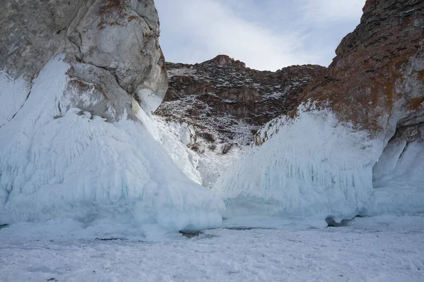 rocks with ice overlaps and icicles near the lake