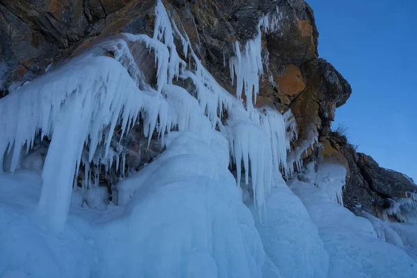 Felsen mit Eisüberschneidungen und Eiszapfen in der Nähe des Sees — Stockfoto