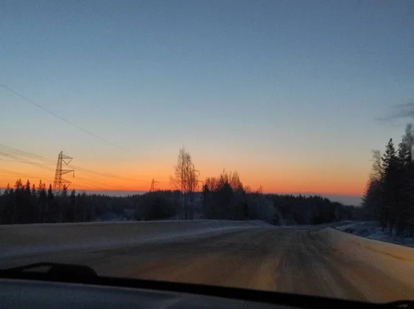 Winter road at sunset with bright red sun — Stock Photo, Image