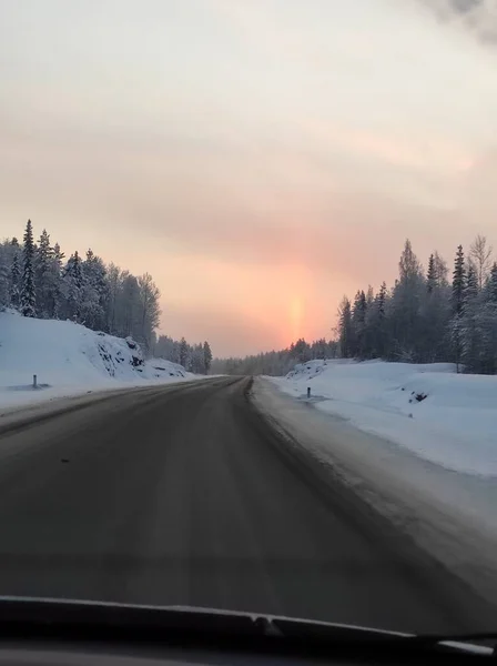 Winter road at sunset with bright red sun — Stock Photo, Image