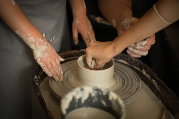 A child and an adult rotate the clay on a potters wheel — 스톡 사진