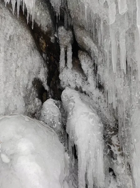 snow icicles and transparent winter patterns on the rocks in the cave