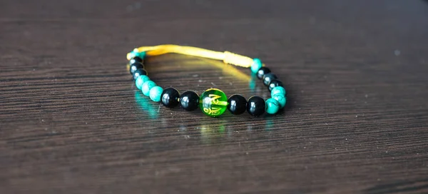 A bracelet with multi-colored stones on a string lies on the table — Stock Photo, Image