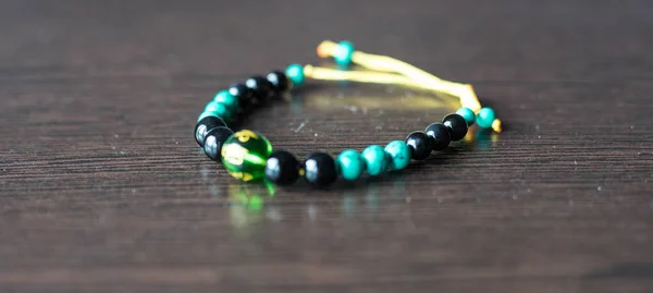 Un bracelet avec des pierres multicolores sur une ficelle repose sur la table — Photo