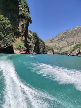 Mavi nehri olan derin bir kanyon ve mavi gökyüzüne karşı güzel dağlar.