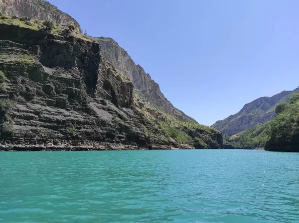 Mavi nehri olan derin bir kanyon ve mavi gökyüzüne karşı güzel dağlar.