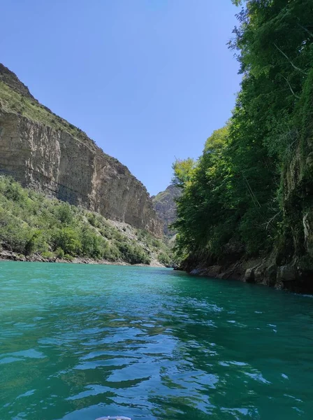 Mavi nehri olan derin bir kanyon ve mavi gökyüzüne karşı güzel dağlar.