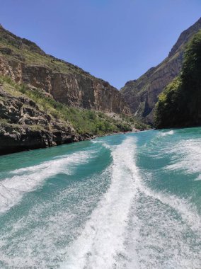 Mavi nehri olan derin bir kanyon ve mavi gökyüzüne karşı güzel dağlar.