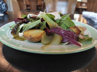 Beyaz tabakta soslu sebze salatası.