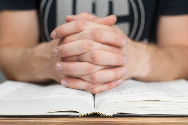 Prayer. Hands on an open Bible in prayer.