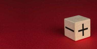 Kırmızı arka planda tahta küp. + ve - küpteki yazıt.