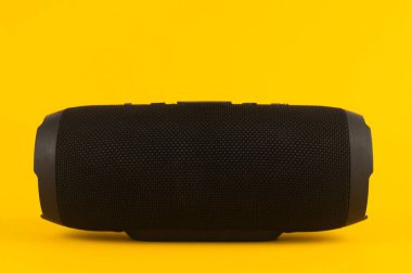 Taşınabilir ses hoparlörü. Siyah müzik hoparlörü. Sarı arka planda