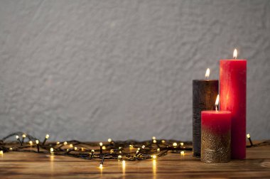 Işıklı mumlar. Arka planda çözünmüş ışık çelenkleri var. Karanlık bir arka planda. Noel kartı..