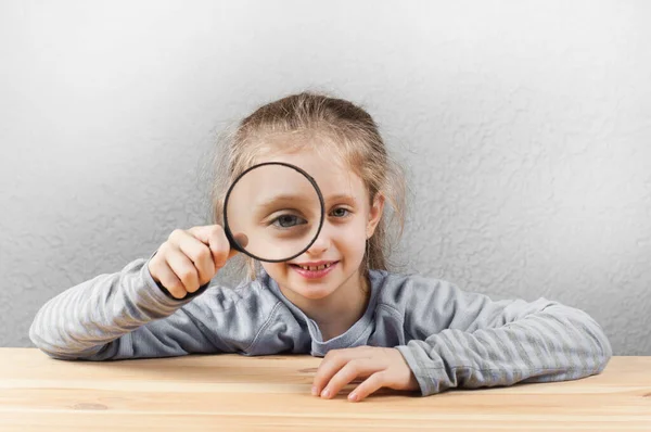 Una Niña Sosteniendo Una Lupa Sus Manos Mientras Está Sentada — Foto de Stock