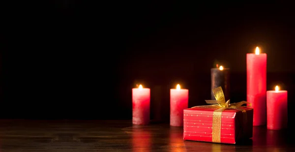 Burning Candles Dark Wooden Table Gift Red Package Gold Bow — Stock Photo, Image