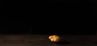 Karanlıkta bir tabakta kruvasan. Minimalizm. Kahvaltı.