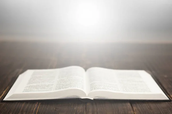 stock image Open book Bible. Light from the book. On a wooden table.