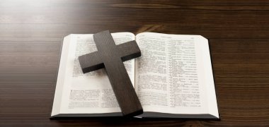 Masanın üzerinde açık İncil kitabı var. İsa 'nın tahta haçı.