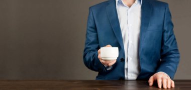 Genç Avrupalı işadamı elinde bir fincan kahve ya da çay tutuyor. Oturuyorum.