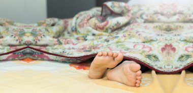 Çocuğun çıplak ayakları yatağın üzerinde. Ayaklar ve topuk.