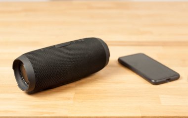 Siyah Portatif Ses Hoparlörü. Tahta bir masada. Hoparlör çalar. Telefon çalıyor.