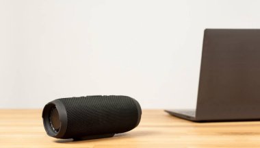 Siyah Portatif Ses Hoparlörü. Tahta bir masada. Hoparlör çalar. Not Defteri.