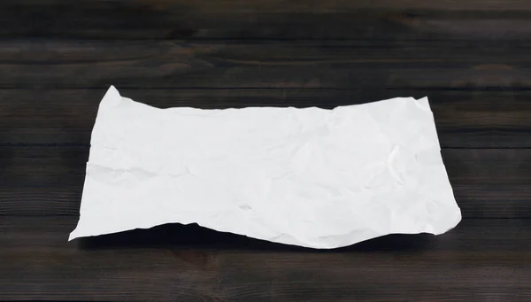 A clean sheet of crumpled paper. A crumpled piece of paper. On a wooden table