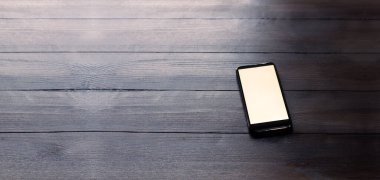 Ahşap bir masada cep telefonu. Beyaz beyaz ekran. Boş tablo.