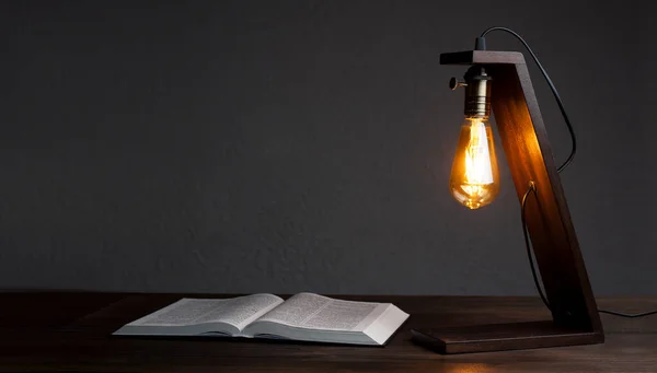 Table lamp and book notepad on the table. Wooden decorative lamp. Night light in the dark.