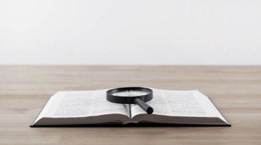 Kitapları aç ve kutsal incili büyüt. Kitabın üzerinde büyüteç var. Tahta bir masada..