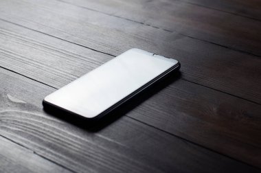Telefon ahşap bir masada. Masaüstü. Boş ekran. Ofiste işyeri.
