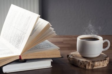 Ahşap bir masada iki kitap. Bir yığın kitap. Bir fincan kahve. İşyeri.