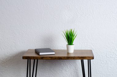 Kapalı defter, not defteri ve kalem. Tahta bir masada, beyaz bir saksıda, yeşil bir saksı. Masaüstü.