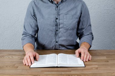 İncil 'i aç. Elinde kitap olan gömlekli bir adam..