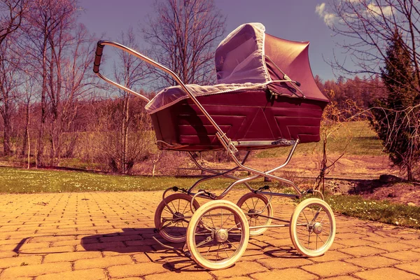 Carruaje de bebé de estilo retro al aire libre en el día soleado, filtro rojo — Foto de Stock
