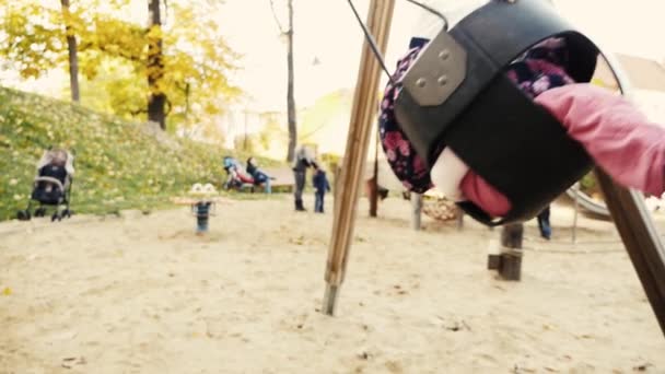 Счастливый ребенок на качелях на детской площадке — стоковое видео