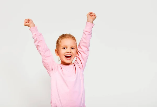 ピンクのスウェットシャツを着た幸せな笑顔の美しい興奮した女の子は カメラを見て白い背景に孤立した手を握っています 広告の無料スペース — ストック写真