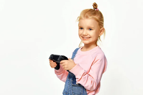 Милая Девочка Играющая Видеоигры Геймпадом Улыбкой Розовой Куртке Джинсовом Комбинезоне — стоковое фото