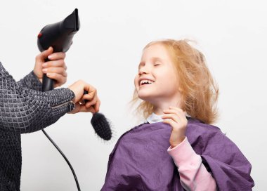 Saç kesme işlemi. Berber dükkanındaki güzel küçük kız, kuaför 4-5 yaşlarındaki şirin beyaz kıza saç stili yapıyor.