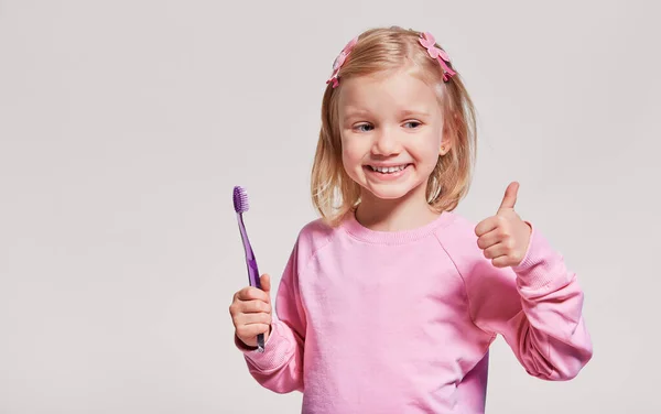 歯ブラシ 歯ブラシ 灰色の背景に笑顔で幸せな子供の女の子 広告のための無料スペース 口腔衛生 — ストック写真