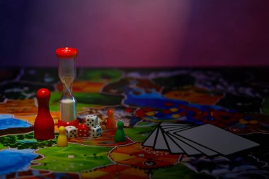 Masa oyunu konsepti. Tahta oyun alanı, bir sürü figür, meeple, zar, bozuk para, kum saati ve bulanık arkaplanda oyun kartları. Metin için boş alan