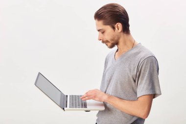 Gri arka planda dizüstü bilgisayar kullanan neşeli bir adamın portresi