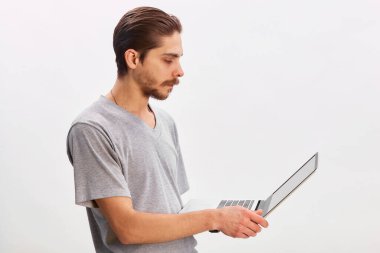 Gri arka planda dizüstü bilgisayar kullanan neşeli bir adamın portresi