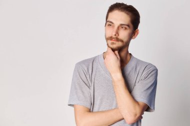 Düşünceli bir adamın portresi. Yakışıklı genç adam gri arkaplan fotokopi alanında izole edilmiş bir şey düşünüyor.