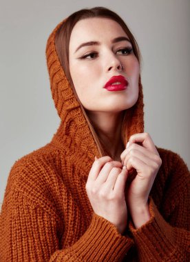 Balıkçı yaka kazaklı, yaka kazaklı genç ve güzel bir kadın. Kırmızı dudaklı sevimli bir kadın model. Stüdyoda, gri arka planda.